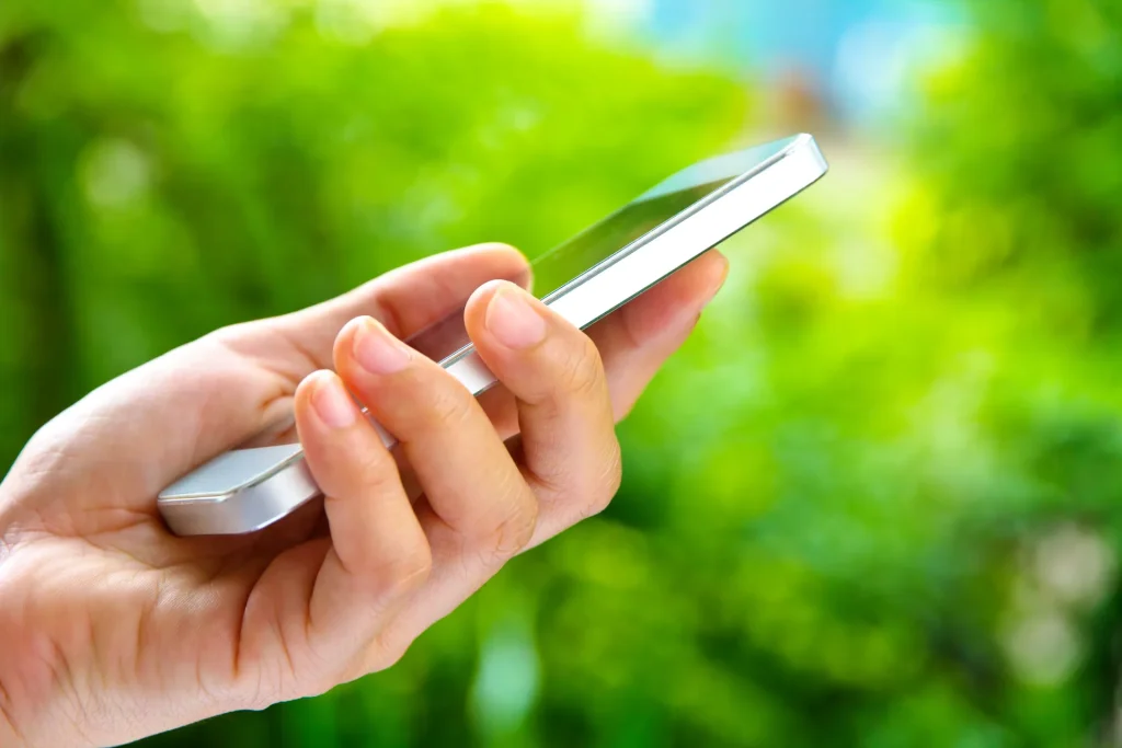 hand holding smart phone in a green background utc